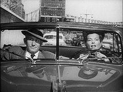 Screenshot of Hepburn and Spencer Tracy sat in an open top car in mid